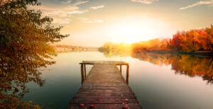 Calming sunset over water with a dock extending outward, representing pause, clarity, and emotional grounding